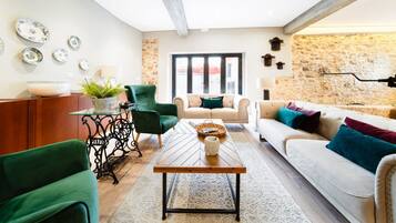 Un salon moderne avec un mur en pierre, une table basse en bois, un canapé et un fauteuil vert.