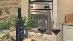 A kitchen counter with a loaf of bread, a bottle of wine, a glass of wine, a knife, and a block of cheese.