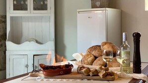 A dining table with bread, a bottle of wine, a pepper shaker, and a bowl of food.