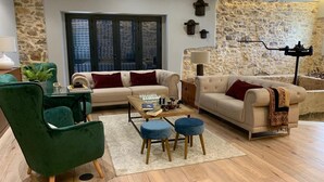 A living room with a stone wall, a green armchair, a beige sofa, and a coffee table.