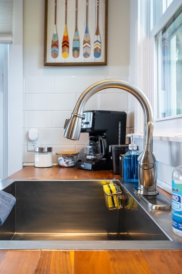 Una cocina moderna con un lavamanos de acero inoxidable, una cafetera y un dispensador de jabón.