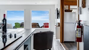 A modern kitchen with a wooden countertop, white cabinets, and a view of the sea. - Lakefront Retreat + Hot Tub • Sunset Views • Point Pelee (Leamington)