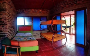 Une chambre avec un lit superposé, un lit simple et une chaise.