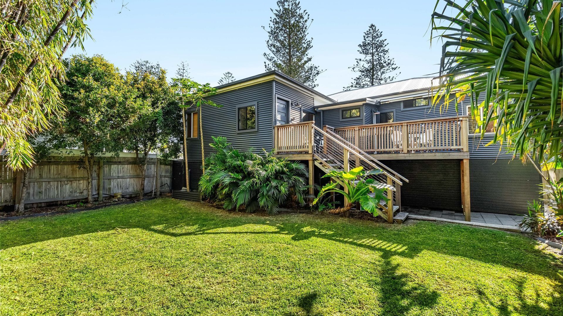A two-story house with a deck and a fenced backyard.