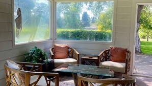 Une véranda avec un toit en verre, des meubles en bois et de grandes fenêtres donnant sur un jardin.