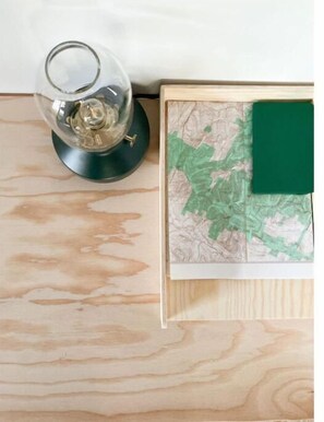Una mesa de madera con una lámpara de vidrio y un libro de mapas.