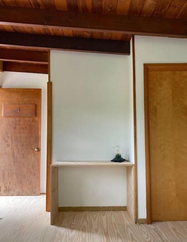 Una habitación con techo de madera, pared blanca y puerta de madera.
