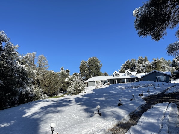 Un paysage enneigé avec une maison et des arbres.