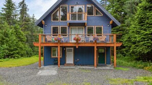 A two-story blue house with a balcony, surrounded by trees. - Spacious rental for 6 in lovely home with gorgeous views, minutes from resort (Girdwood)