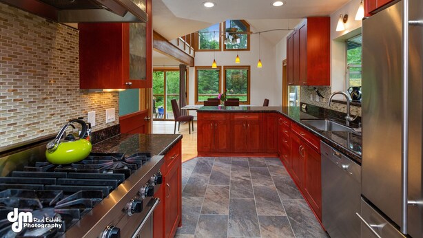 A modern kitchen with a gas stove, stainless steel appliances, and wooden cabinets. - Spacious rental for 6 in lovely home with gorgeous views, minutes from resort (Girdwood)