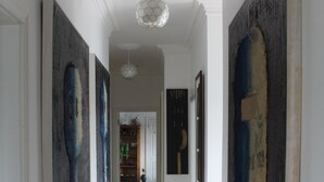 A hallway with wooden flooring, white walls, and several abstract paintings. - SolasTobann Room 1 En-suite Malin Head  (Malin Head)