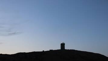 Silhouet van een heuvel met een torenachtige constructie erop.