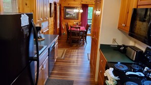 Cucina in legno con frigorifero, piano cottura e zona pranzo.