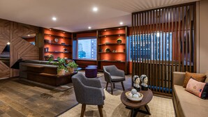 A modern living room with a sofa, armchairs, a coffee table, and a bookshelf.