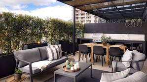 An outdoor patio with a sofa, chairs, a table, and a grill area.