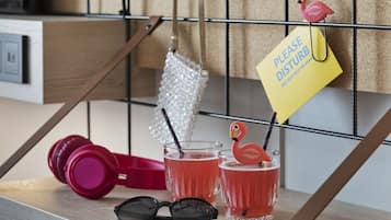 A kitchen counter with a pink handbag, a pair of sunglasses, and two glasses of red drink with flamingo decorations.