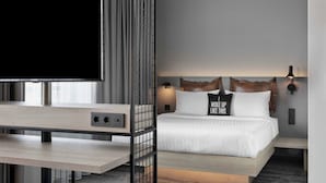 Una habitación de hotel moderna con una cama grande, un televisor y un escritorio con una computadora.