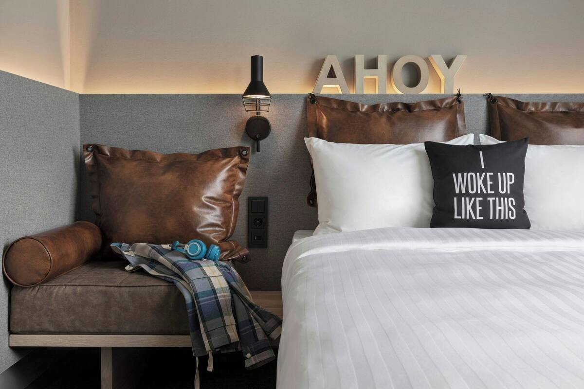 Una habitación de hotel moderna con cama, sofá y una lámpara fijada a la pared.