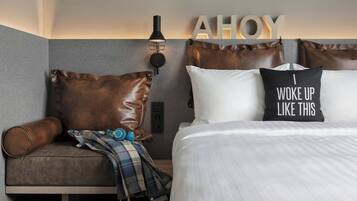 A modern hotel room with a bed, a sofa, and a wall-mounted light fixture.