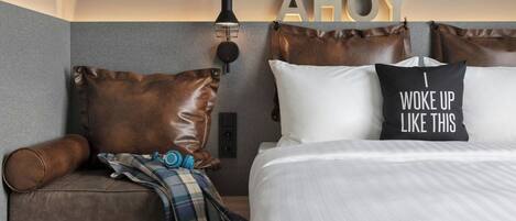 Une chambre d’hôtel moderne équipée d’un lit, d’un canapé et d’un luminaire fixé au mur.