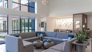 Una sala moderna con un sofá modular, otomanas redondas y una mesa de centro. Una ventana grande proporciona luz natural y vistas al exterior.