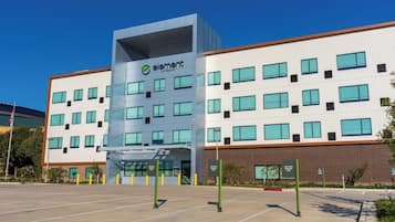 Un edificio moderno con un letrero llamativo de 'element by Westin', múltiples ventanales y un estacionamiento con letreros que indican 'Solo coches compartidos'.