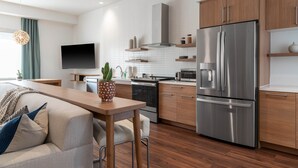 Una cocina moderna con electrodomésticos de acero inoxidable, armarios de madera y una zona de comedor con mesa y sillas.