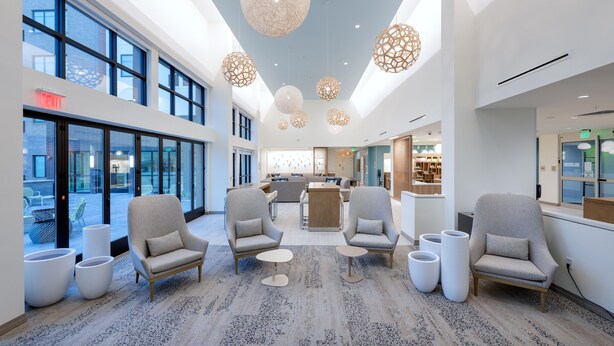 Un vestíbulo amplio con mobiliario moderno, ventanas grandes y lámparas esféricas decorativas.