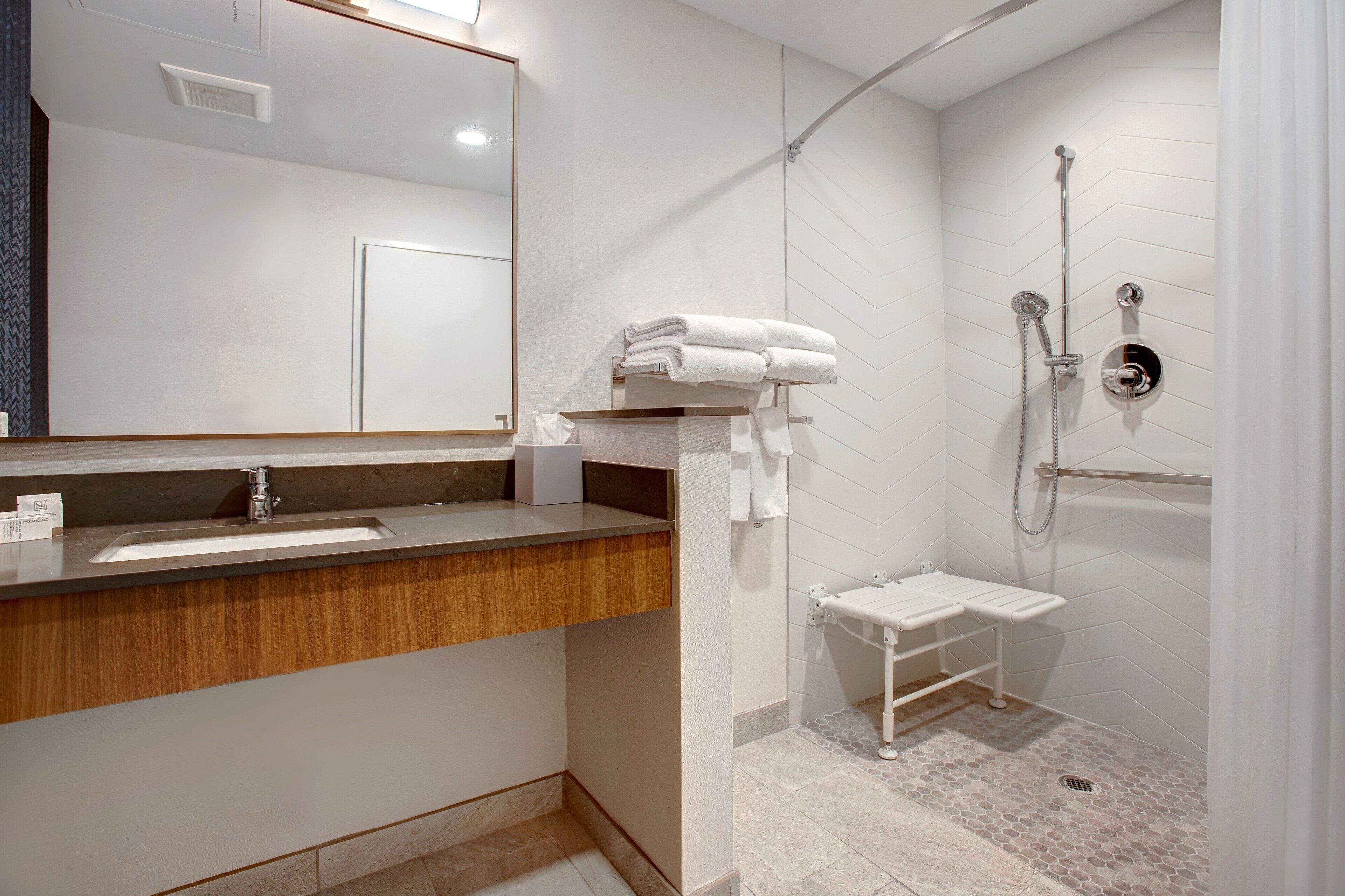 Un baño moderno con lavabo, espejo y ducha.