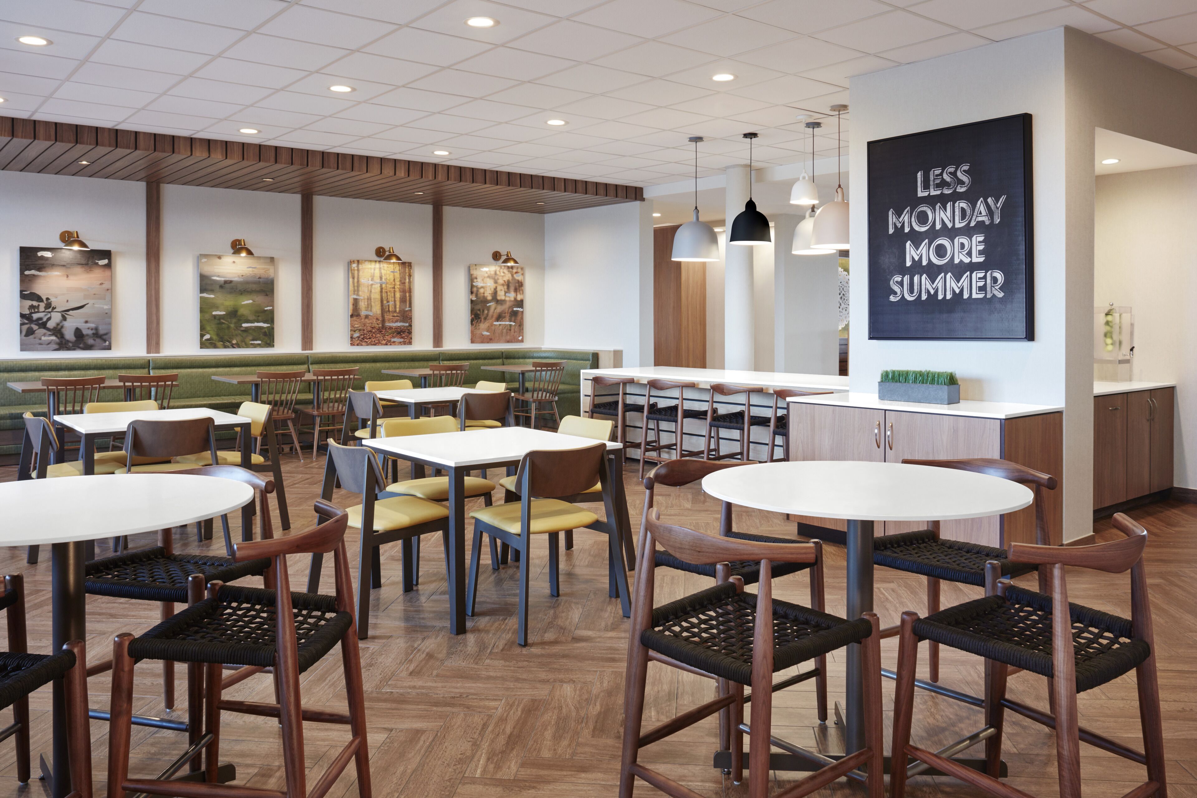 A modern dining area with round tables and chairs, wooden flooring, and artwork on the walls.