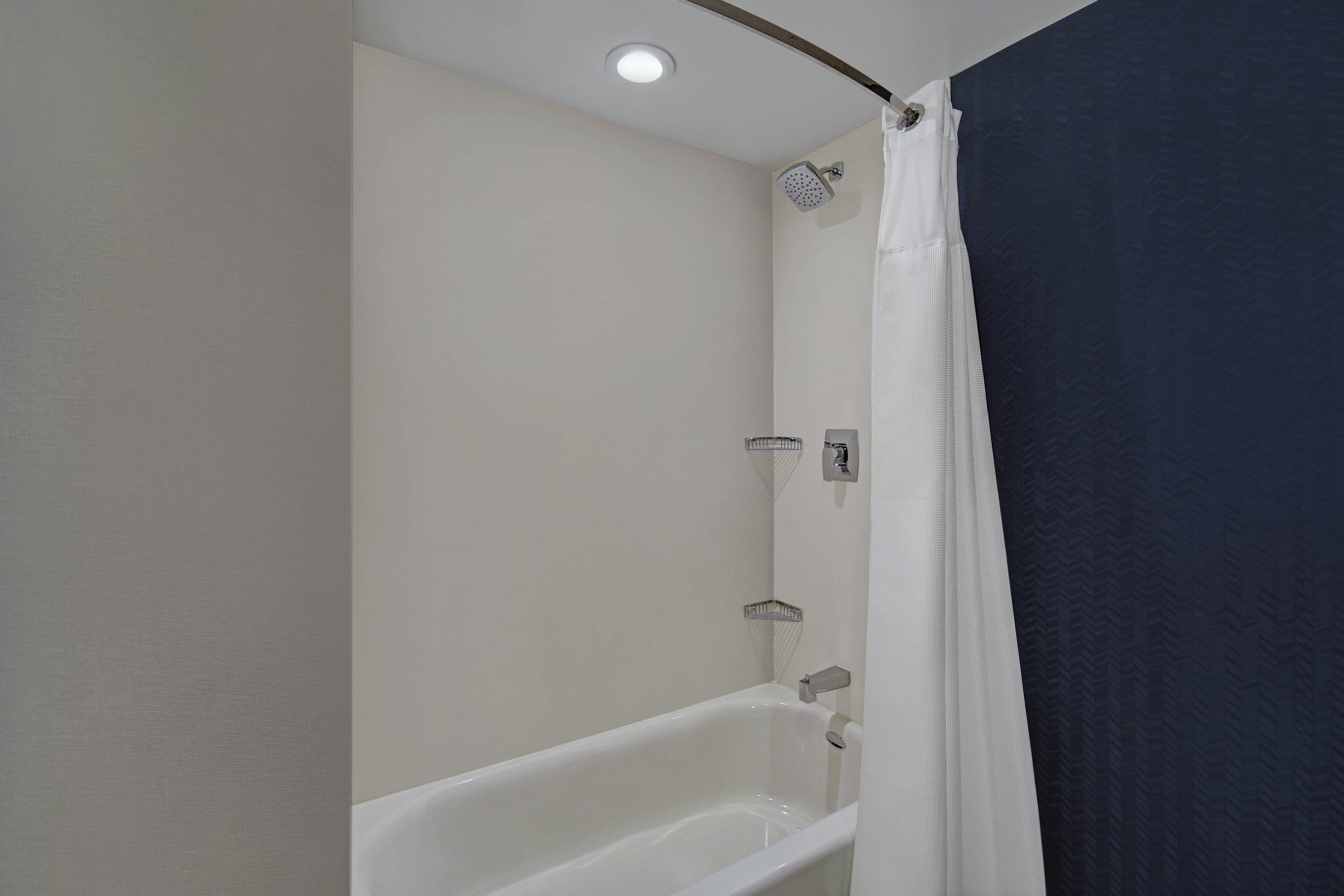 Un baño con una bañera blanca, un cabezal de ducha y un perchero para toallas.