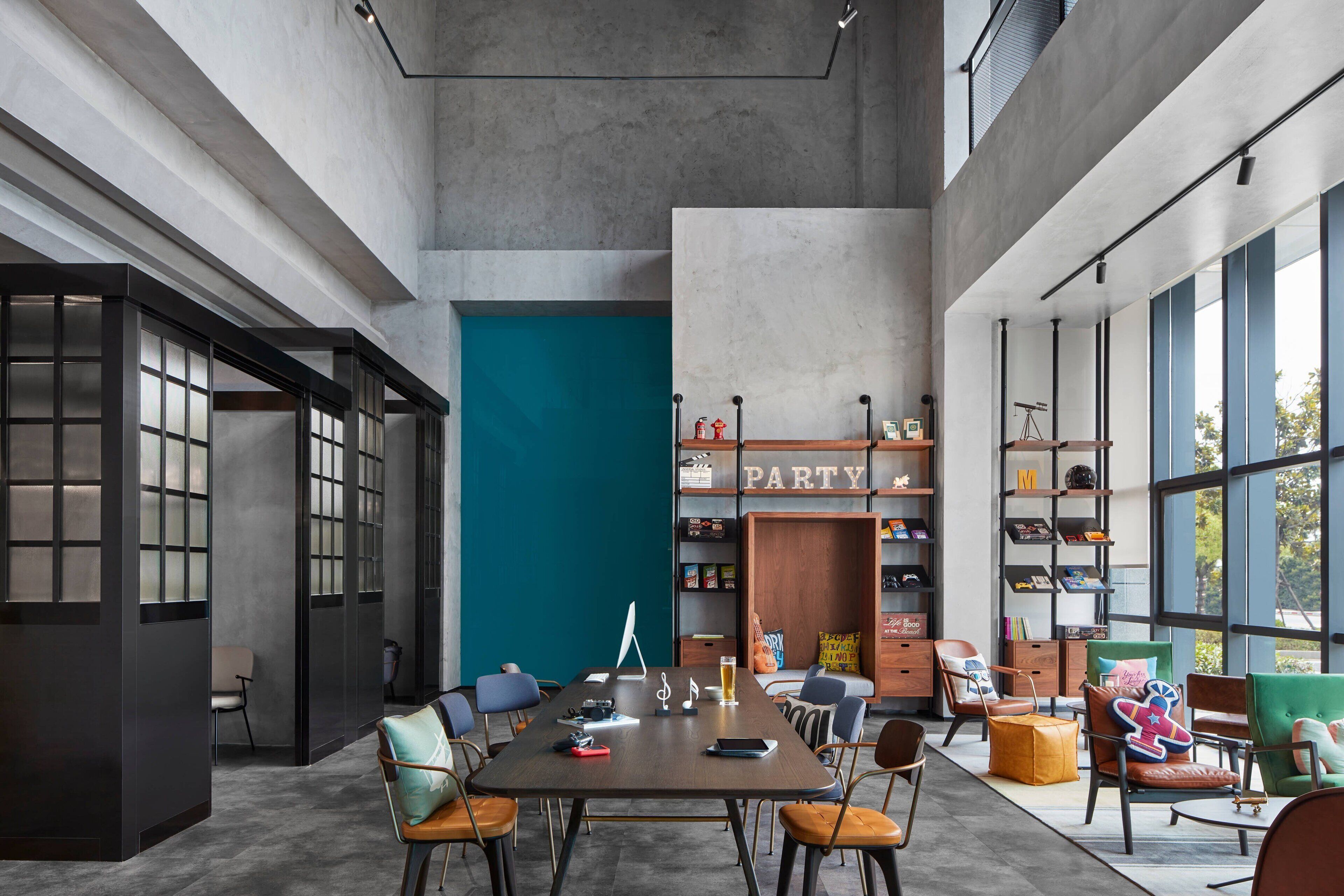 A spacious room with a large table, chairs, and a bookshelf.