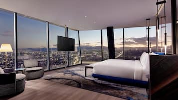 A modern hotel room with a large bed, a TV, and a city view.