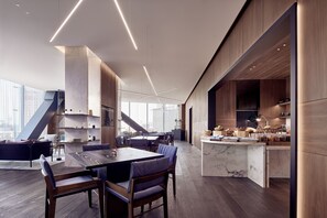 A modern kitchen with a marble island, wooden cabinets, and a dining area with a large table and chairs.