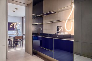 A modern kitchen with dark blue cabinets, a round dining table, and pendant lights.