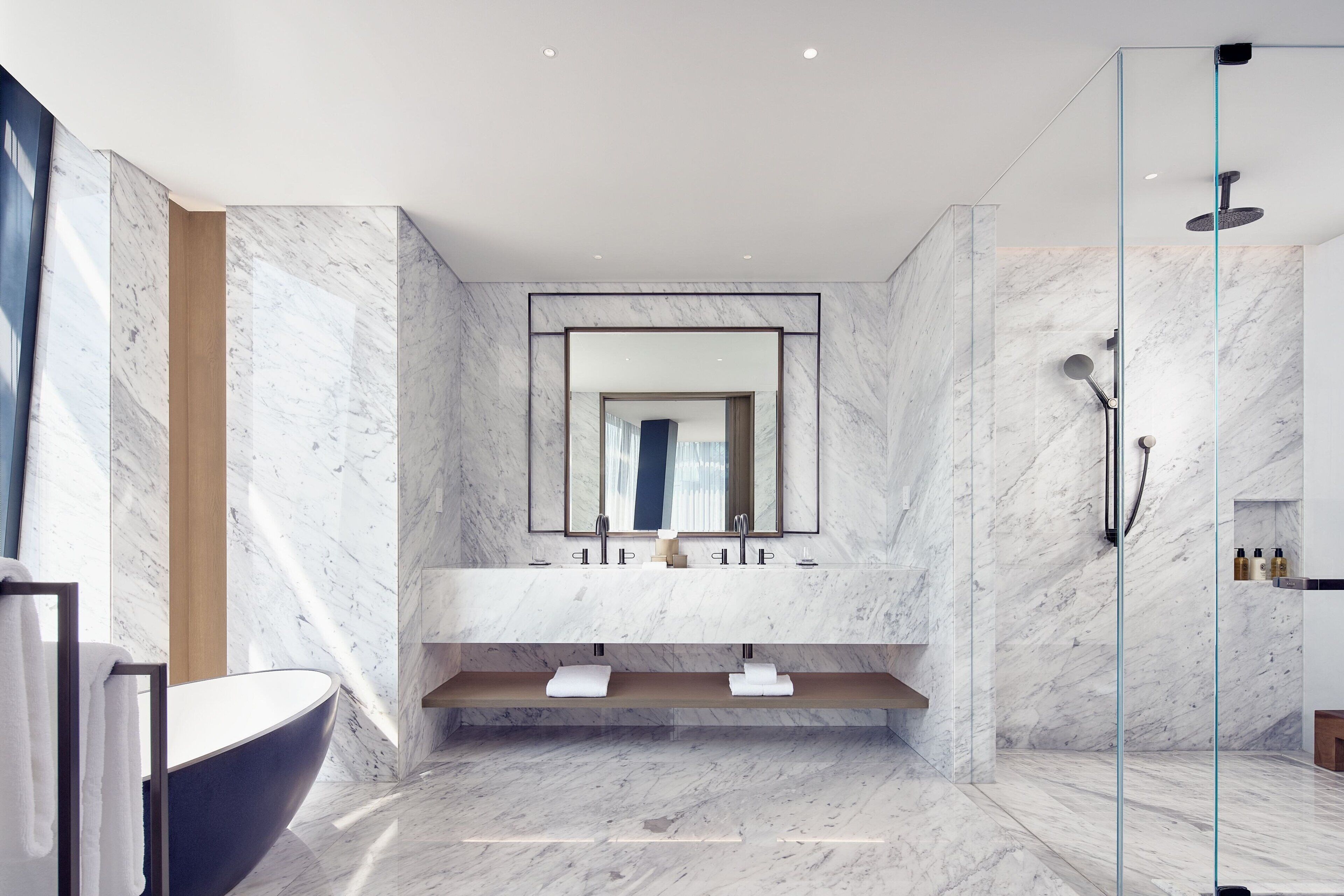 Un baño moderno con tocador de mármol, bañera independiente y cabina de ducha con mampara de vidrio.