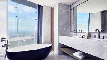 Un baño moderno con una bañera independiente, un espejo grande y un tocador doble.