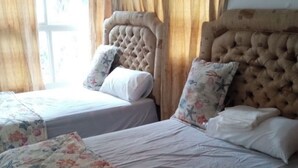 A hotel room with two beds, each with a floral-patterned bedspread and a tufted headboard. - Beach house (Cumayasa)