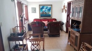 A dining area with a glass table, wicker chairs, and a red patterned sofa. - Beach house (Cumayasa)