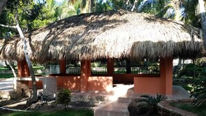 A thatched-roof structure with a tiled walkway leading to it. - Beach House ( Hidden Paradise  (Cumayasa)