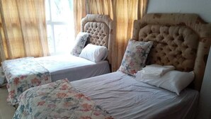 A room with two beds, each with a floral bedspread and a headboard. - Beach House ( Hidden Paradise  (Cumayasa)