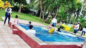 A swimming pool with a tiled deck, surrounded by greenery and palm trees. - Beach House ( Hidden Paradise  (Cumayasa)