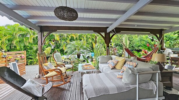 An outdoor covered patio with a hammock, rocking chair, and cushioned seating. - Creole charm with modern comforts (Sainte-Anne)