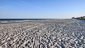 A wide sandy beach with visible tire tracks and a clear blue sky. - Couple’s Retreat w/ Balcony in Surfside Beach! (Surfside Beach)