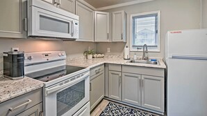 A kitchen with white cabinets, a built-in microwave, a Keurig coffee maker, a sink, and a refrigerator. - Couple’s Retreat w/ Balcony in Surfside Beach! (Surfside Beach)
