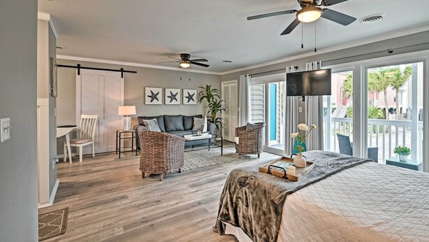 A spacious bedroom with a large bed, two wicker chairs, a sofa, a TV, and a balcony with a view. - Couple’s Retreat w/ Balcony in Surfside Beach! (Surfside Beach)
