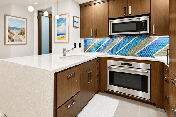 A kitchen with wooden cabinets, a stainless steel microwave, and an oven.