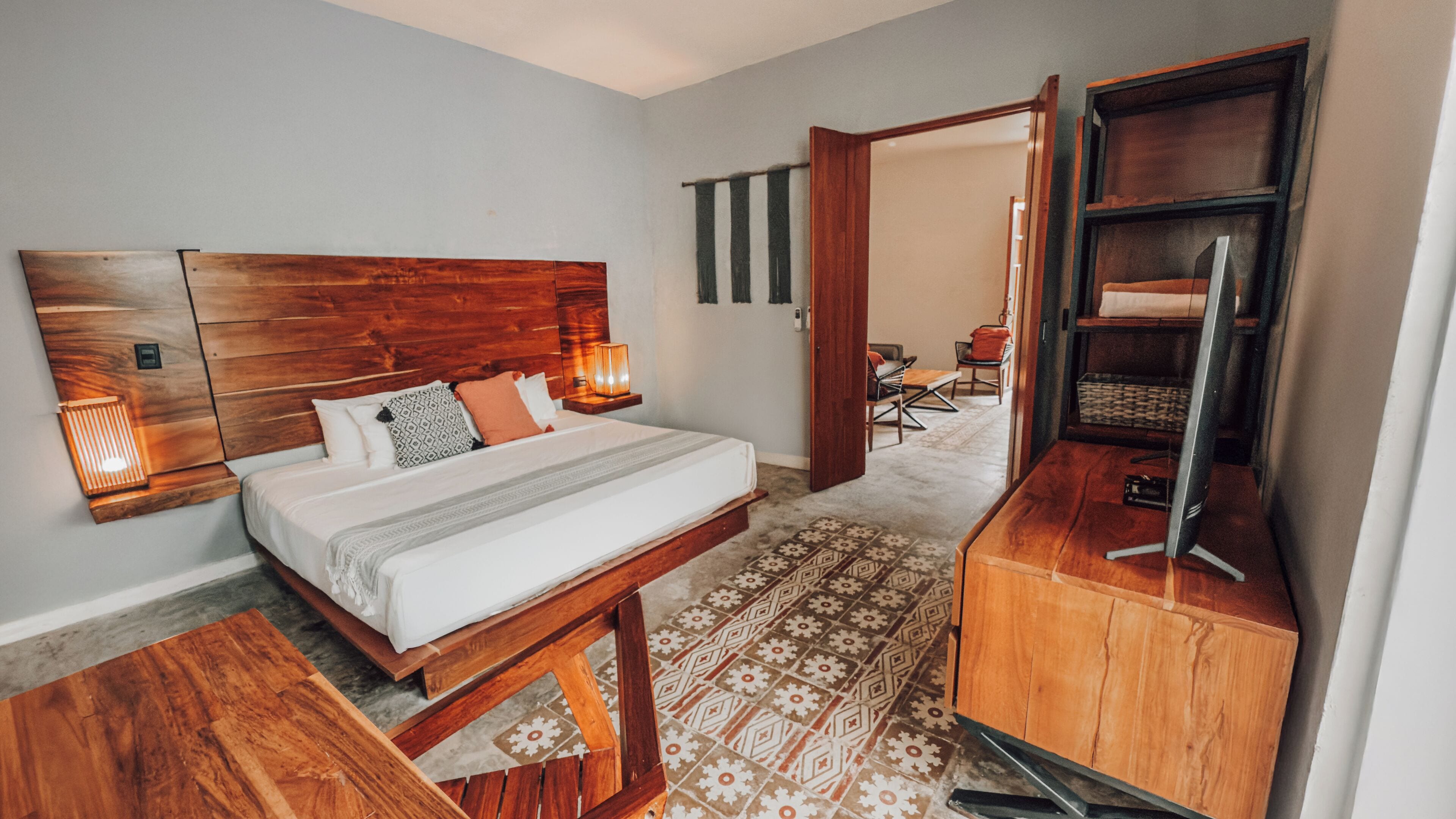 Una habitación de hotel con una cama de madera, lámparas de noche, un escritorio y un televisor.