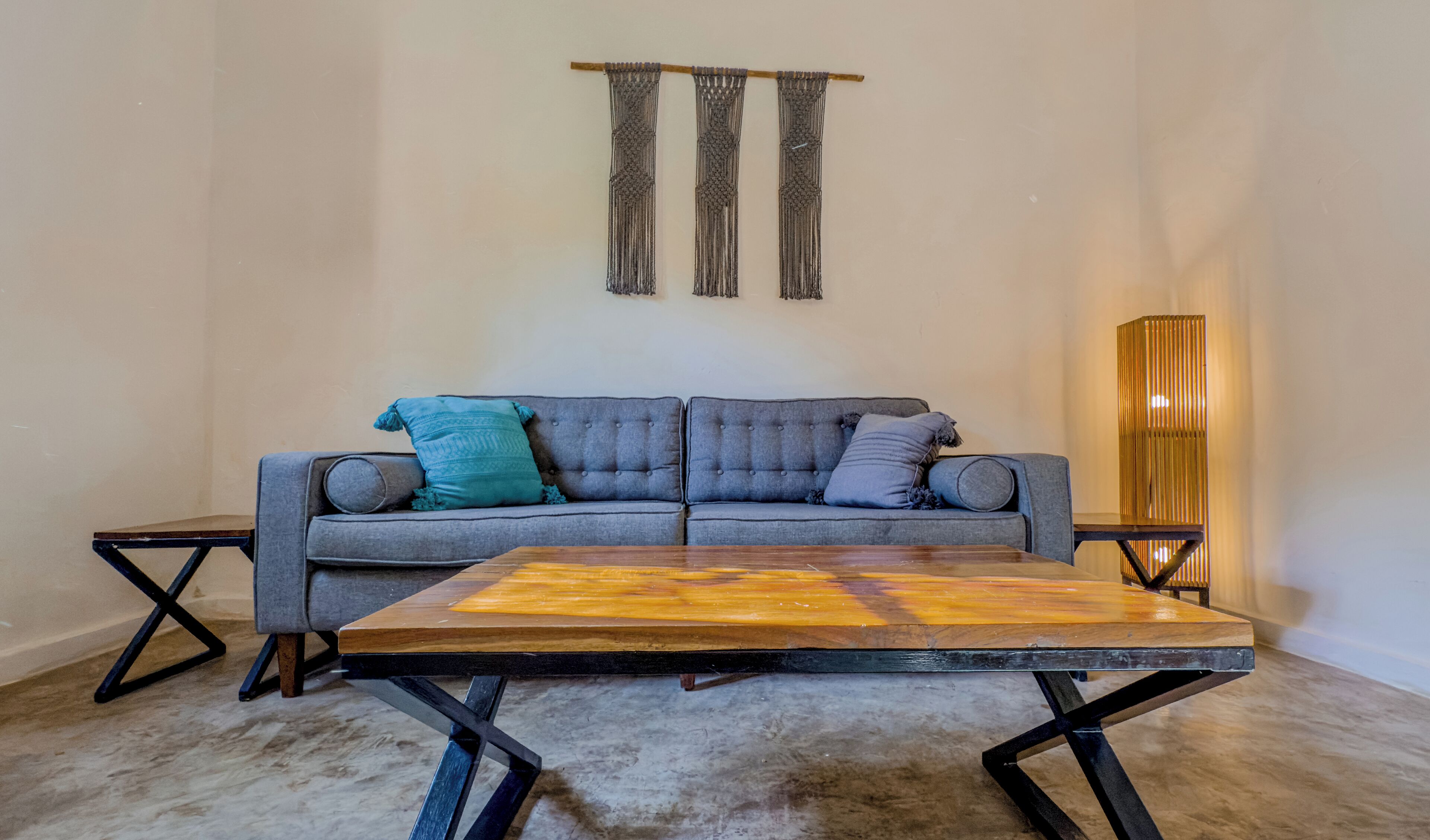Un salon moderne avec un canapé gris, une table basse en bois et un grand lampadaire.