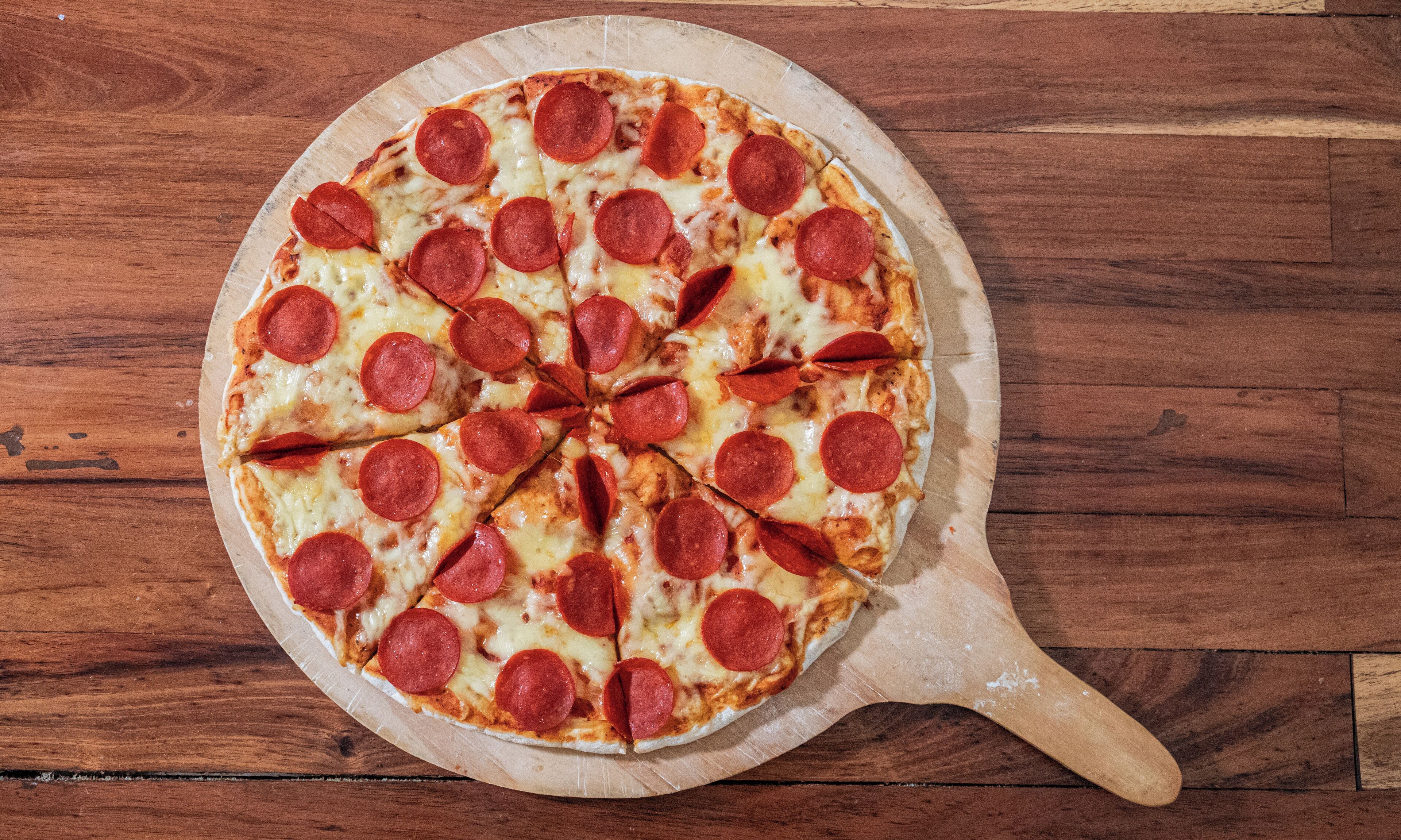 En pepperoni pizza på en træbræt.